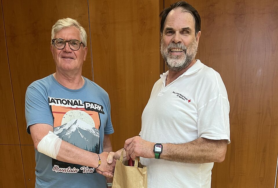 Gratulation für Jörg Böhm zur 50. Blutspende Norbert Finger gratuliert Frau Jeromin zur 50. Blutspende mit einem Präsent in einem Papierbeutel. Beide stehen nebeneinander und freuen sich zu diesem Anlass.