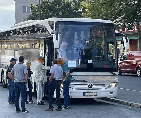 Mehrere Personen besteigen einen weißen Reisebus