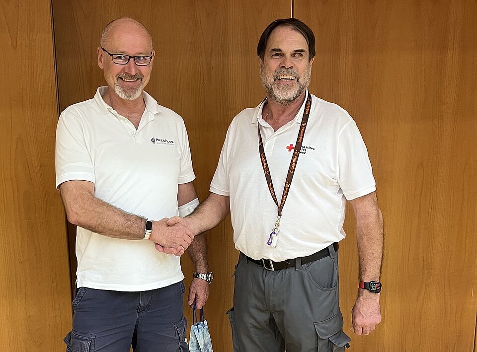 Gratulation zur 50. Blutspende Norbert Finger (2. Vorsitzender des DRK Kelkheim) gratuliert Herrn Wolfgang Huber zu seiner 50. Blutspende. Beide stehen vor einer holzvertäfelten Wand. Norbert Finger gratuliert per Handschlag.