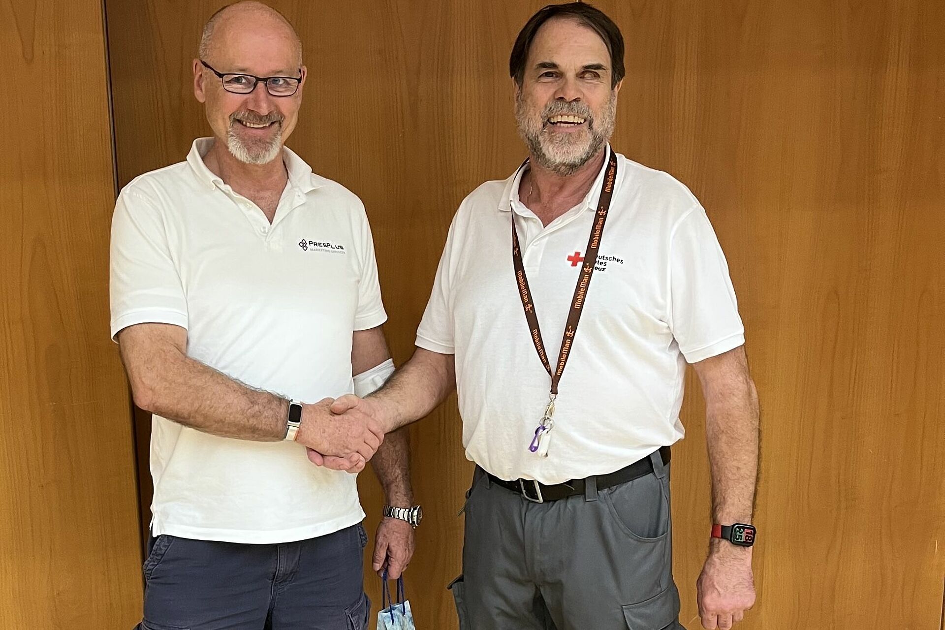 Norbert Finger (2. Vorsitzender des DRK Kelkheim) gratuliert Herrn Wolfgang Huber zu seiner 50. Blutspende. Beide stehen vor einer holzvertäfelten Wand. Norbert Finger gratuliert per Handschlag.